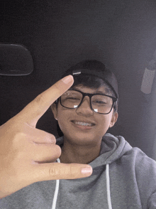a young man wearing glasses and a black hat is giving the peace sign