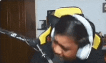 a person wearing headphones and a hat is sitting in front of a microphone in a room .