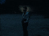 a man in a blue shirt with suspenders is standing in the dark
