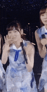 a woman in a blue dress is holding a microphone and making a peace sign