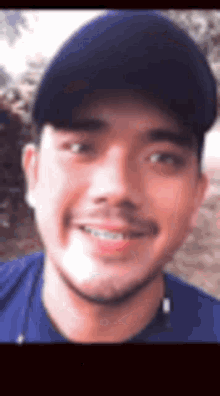 a man wearing a baseball cap and a blue shirt is smiling .