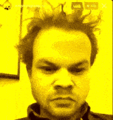 a close up of a man 's face with a yellow background and a live button in the corner
