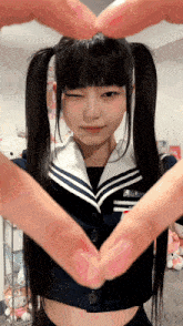 a girl in a sailor suit making a heart with her hands