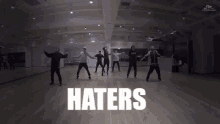 a group of people are dancing in a dance studio with the words `` haters '' written above them .