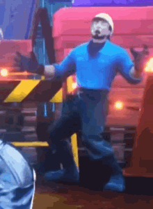 a man in a blue shirt is standing in front of a red truck .