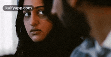 a man and a woman are looking at each other with a blurry background .