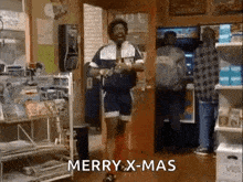 a man is dancing in a store with the words merry x-mas written on the screen .