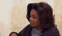 oprah winfrey is holding a doll in her arms and making a face .