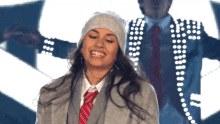a woman wearing a hat and a tie is smiling