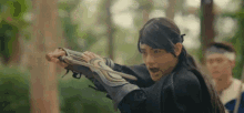 a young man in a costume is holding a sword in his hand .