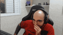 a bald man wearing headphones and a red shirt that says aomium
