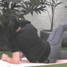 a woman in a black shirt is laying on a pink mat