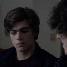 a close up of a young man 's face with a black jacket on