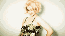 a woman with blonde hair is wearing a green and black floral dress