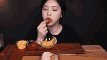 a woman is sitting at a table eating a taco with sauces on it .