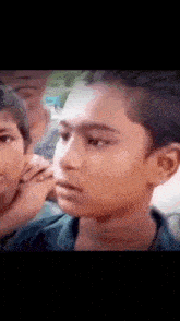 a close up of a boy 's face with a group of people behind him .
