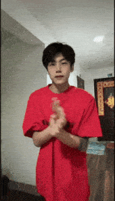 a young man in a red shirt is clapping his hands in a room