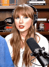 a woman wearing headphones and a microphone is sitting in front of a microphone .