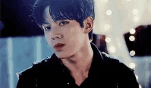 a close up of a young man 's face with a black shirt on .
