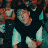 a man smoking a cigarette in a crowd of people with a t-shirt that has the letter s on it