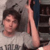 a young man wearing a gray t-shirt with the letter a on it is giving a high five