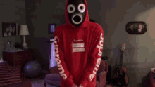 a person wearing a mask and a red hoodie with the letter o on it