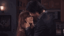 a man and woman are kissing in a kitchen in front of a microwave