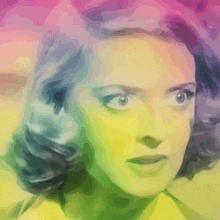 a close up of a woman 's face with a rainbow of colors behind her