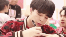 a young man is sitting at a table holding a pen in his hand .
