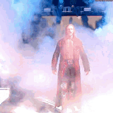 a man in a trench coat is walking through a cloud of smoke with the hashtag #thenextround