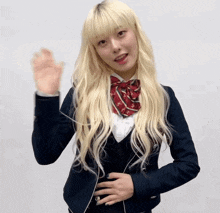 a girl with blonde hair is wearing a school uniform and a red bow tie
