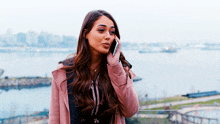 a woman in a pink coat talking on a cell phone