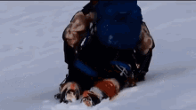 a person is kneeling down in the snow with a backpack on their back