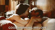a man and a woman are kissing on a bed with the words `` good morning my love '' .