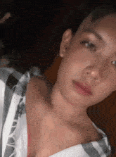 a close up of a young man 's face with a plaid shirt on
