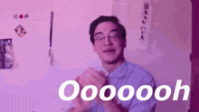 a man wearing glasses is clapping his hands in a room with purple lights .