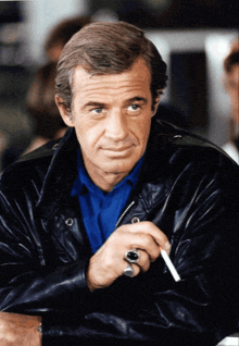 a man with a ring on his finger holds a cigarette in his hand