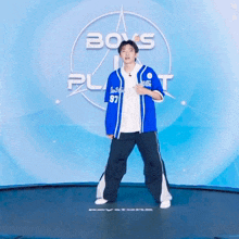 a boy is standing on a trampoline in front of a sign that says " boys planet "
