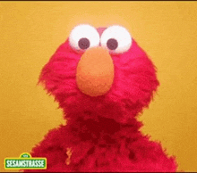 elmo from sesame street is standing in front of a yellow background and making a funny face .