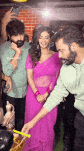 a woman in a pink saree is standing next to a man in a green shirt
