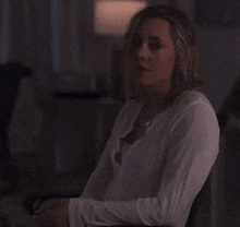 a woman wearing a white shirt is sitting in a chair