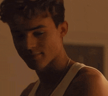 a close up of a young man 's face with a white tank top on