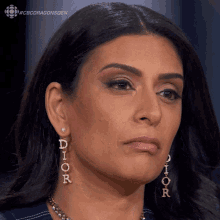 a woman wearing a pair of dior earrings looks at the camera