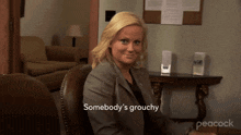 a woman sitting in a chair with the words somebody 's grouchy written below her