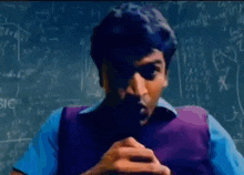 a man is sitting in front of a blackboard with equations on it