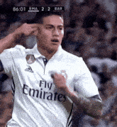 a soccer player wearing a fly emirates shirt celebrates his goal