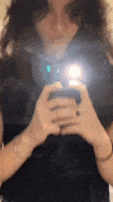 a woman is taking a picture of herself in the mirror with her phone .