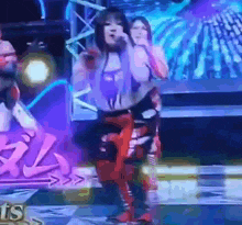 a woman is singing into a microphone while dancing on a stage in front of a crowd .
