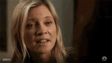 a woman with blonde hair is making a funny face and looking at the camera .