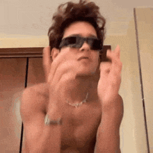 a shirtless man wearing sunglasses is making a funny face .
